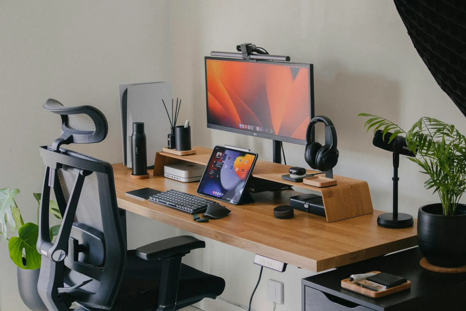 Un poste de travail aménagé et ordonné : bureau en bois, siège ergonomique, casque et plantes