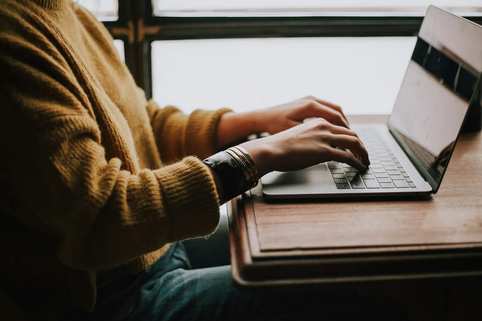 Une personne concentrée sur son travail devant un ordinateur portable.